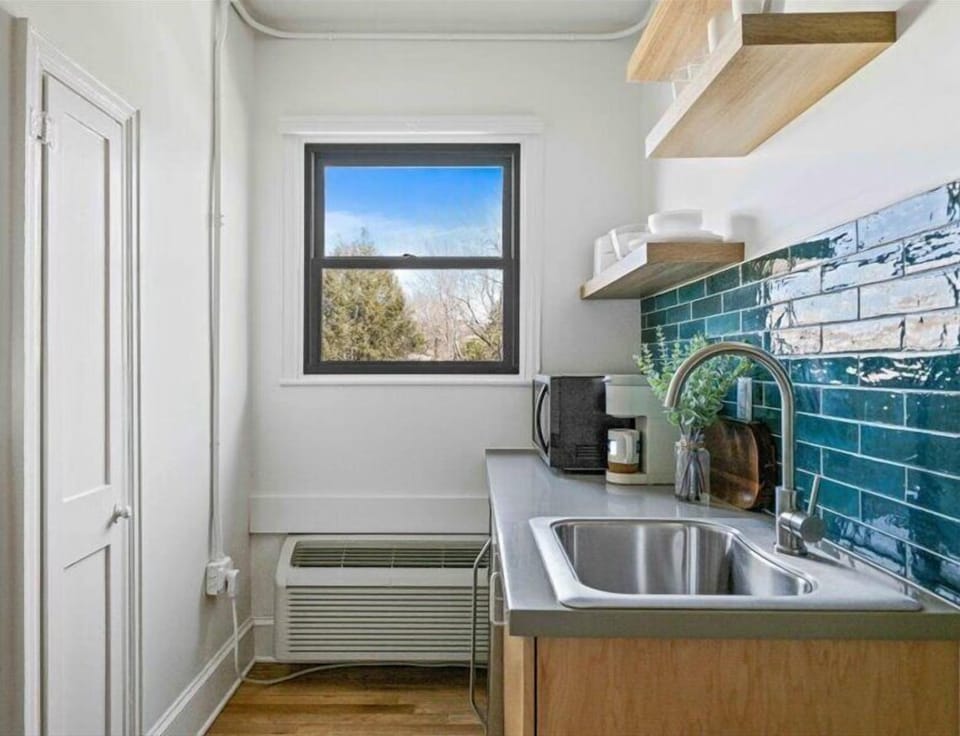 Bright kitchenette with modern finishes, featuring a mini fridge, microwave, coffee setup, and everything needed for easy, convenient meals.