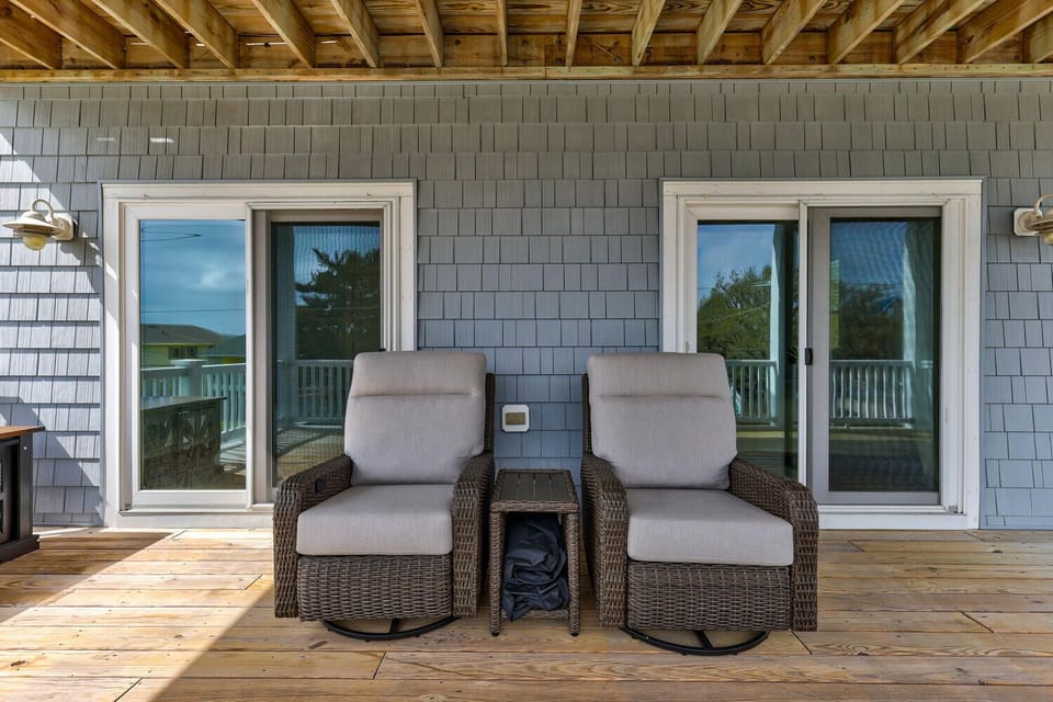 Unwind in plush swivel chairs on your private deck, where comfort meets coastal charm under natural wood beams.