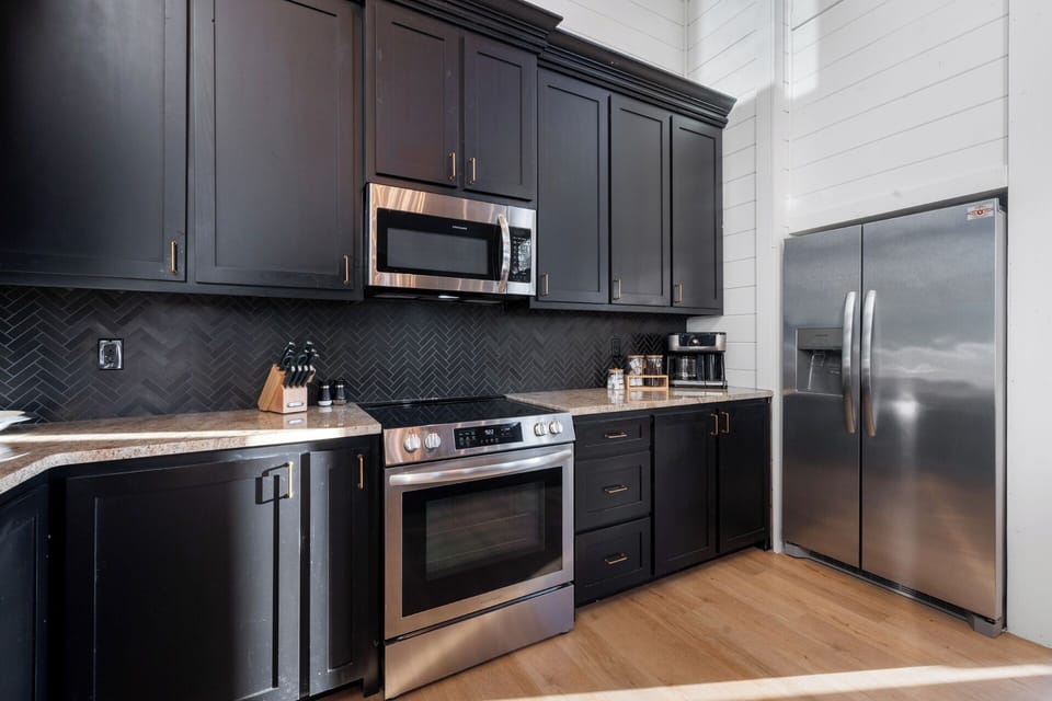 Fully equipped kitchen with modern appliances and a stocked coffee bar—complete with complimentary coffee, K-cups, creamers, and sugar