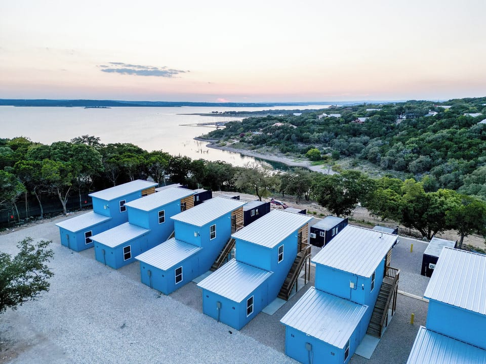 Vibrant blue cabins nestled between lush hills and serene lake waters