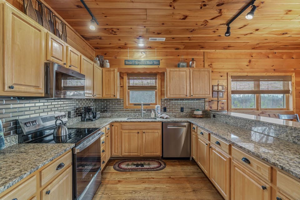 Cook memorable meals in this fully-equipped kitchen with granite counters, stainless appliances, and warm wood finishes throughout your cabin retreat.