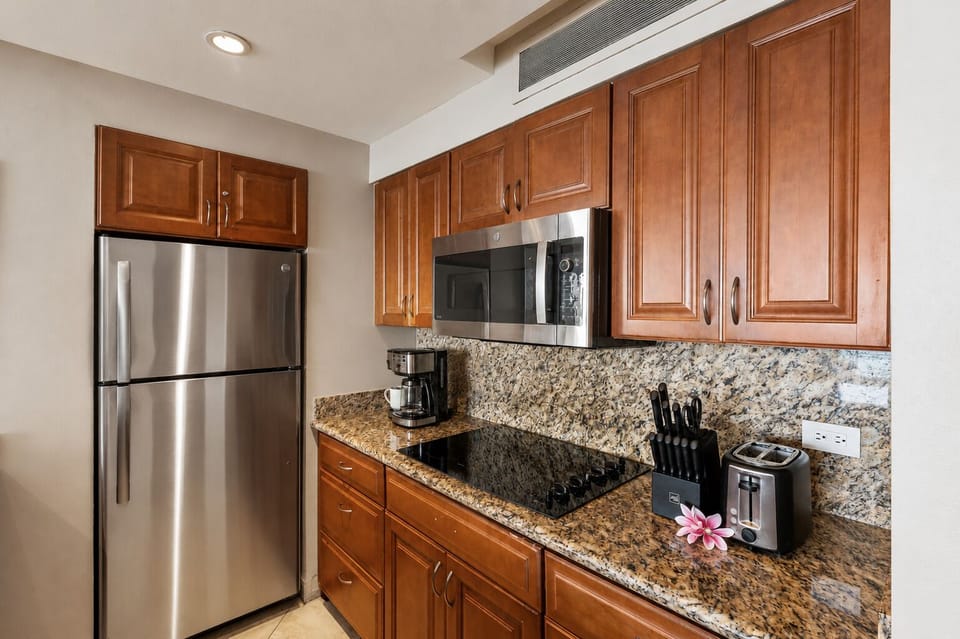 Fully equipped kitchen with granite counters, coffee maker, and ample storage.