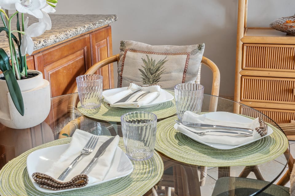 Dining table set for three with island-style decor and natural light.
