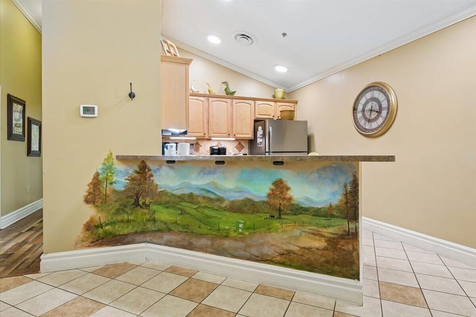 Your fully equipped kitchen features a stunning hand-painted landscape mural, creating an inspiring backdrop for your culinary adventures.