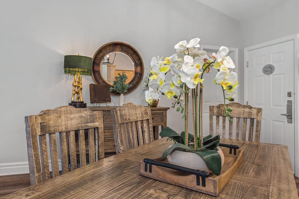 Gather around this rustic dining table with elegant orchid centerpiece, where memorable meals await in your beautifully appointed space.