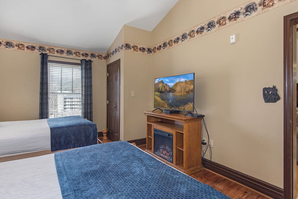 Relax in your cozy bedroom with twin beds, flat-screen TV, and warming fireplace creating the perfect retreat.