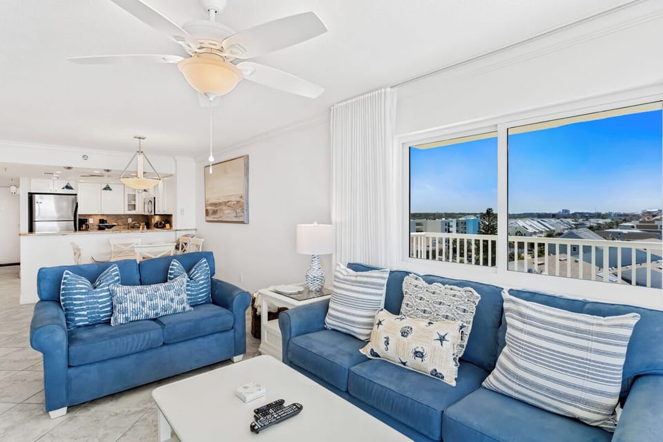Relax in your bright coastal living room with comfortable blue sofas and stunning city views from your private balcony.