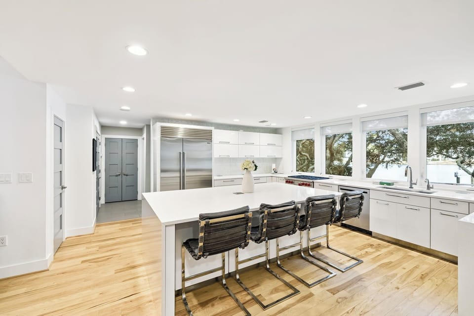 Your sleek modern kitchen awaits with pristine white countertops, top-tier appliances, and gorgeous tree views through expansive windows.