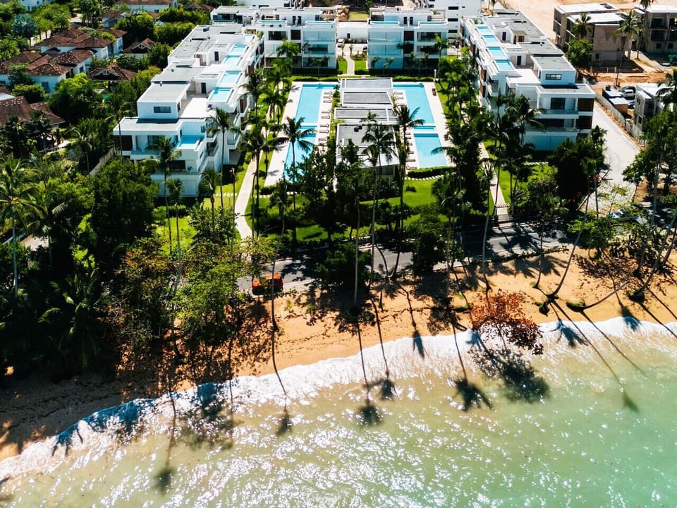 Aerial view of the property just steps from the beach—easy access to the shoreline and surrounded by well-kept grounds and shared pool areas.