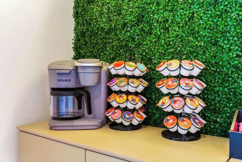 Fully stocked coffee bar with Keurig, electric tea kettle, assorted K-Cups, creamer, and sweeteners.