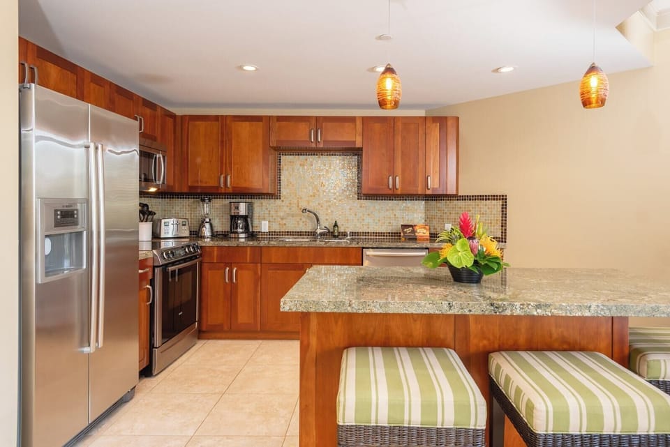 Full kitchen with bar seating, granite counters, pendant lighting, and top-tier appliances for your stay HKH-423