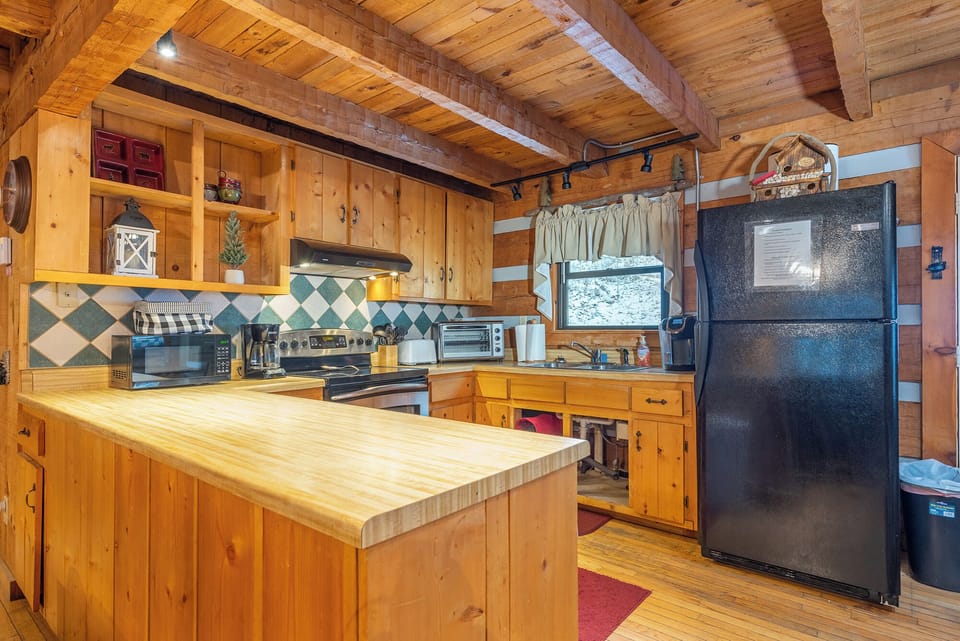 Fully equipped rustic kitchen with wood cabinetry and spacious counter space. Perfect for preparing meals during your cabin stay.