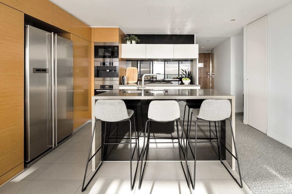 Modern fully equipped kitchen with stone island bench, bar stools, quality appliances and plenty of space for coffee, platters or a relaxed meal at home.