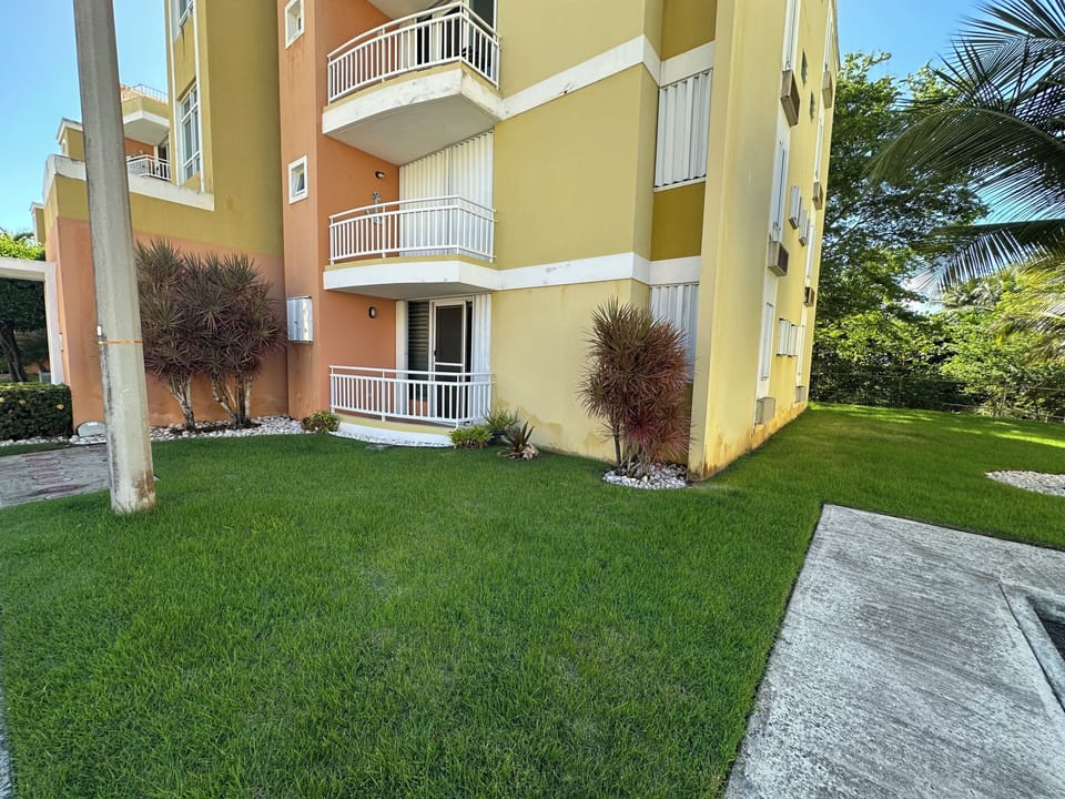 Modern apartment buildng with private balconies and lush, manicured green lawns.