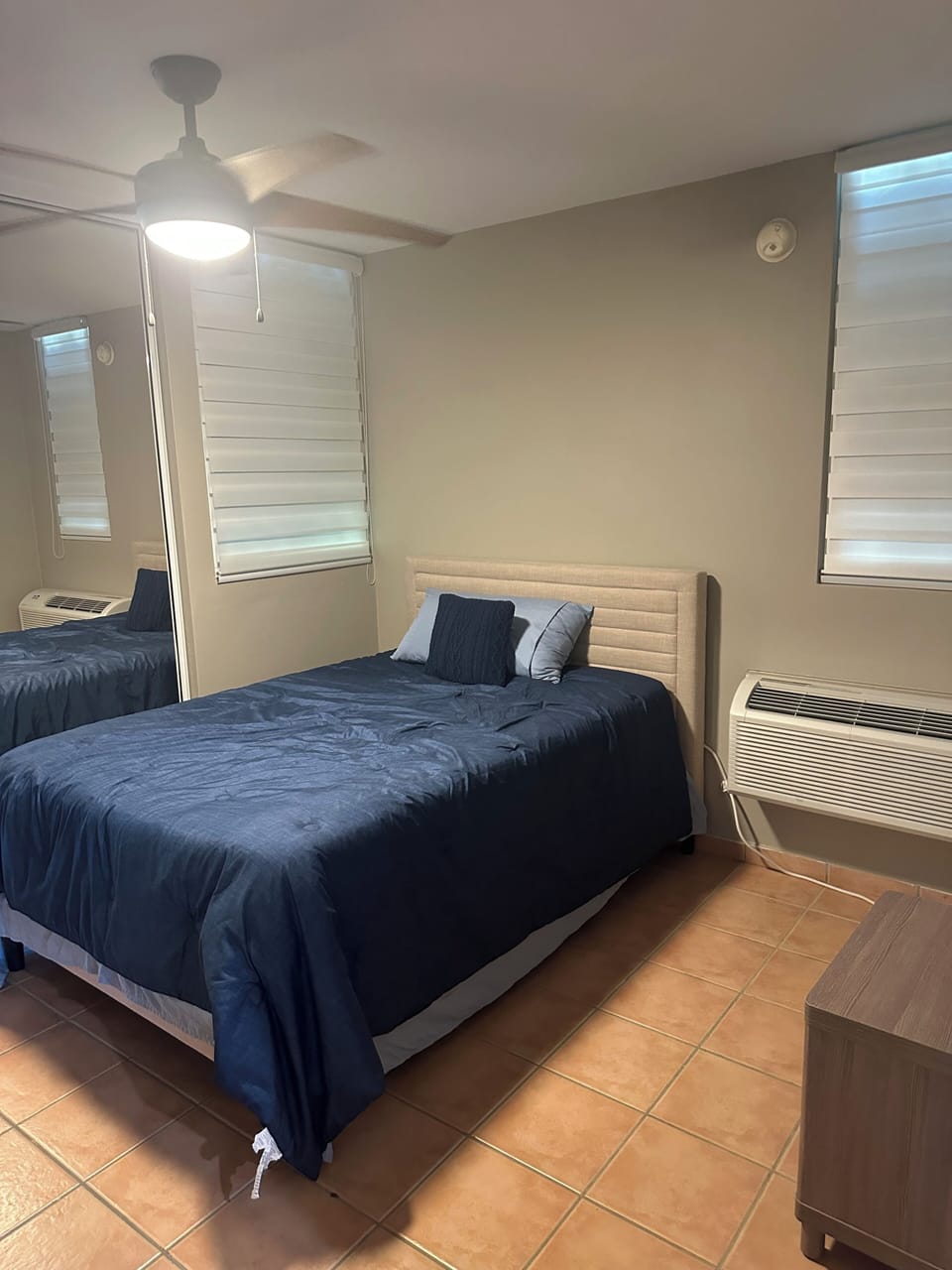 Inviting bedroom featuring mirrored closets, air conditioning, and tiled floors.