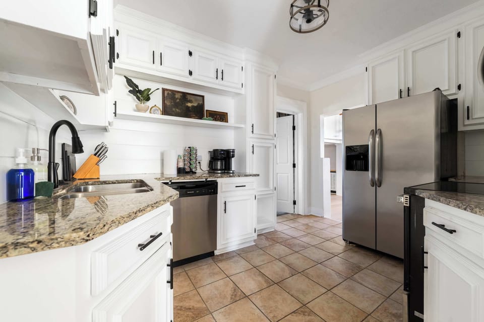 This bright, modern kitchen features sleek stainless steel appliances, including a spacious refrigerator and a dishwasher for stress-free cleanup. The granite-style countertops and crisp white cabinetry provide ample room to prep your favorite vacati