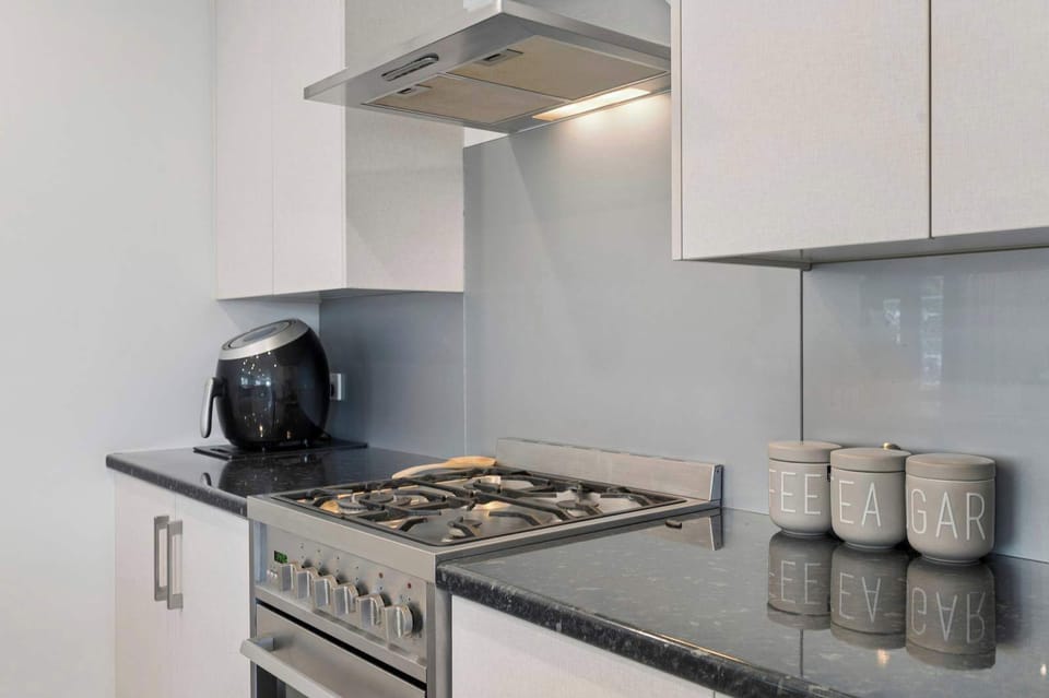 Stainless steel gas range and rangehood with granite benchtops — gourmet kitchen appliances at this self-contained Rotorua rental