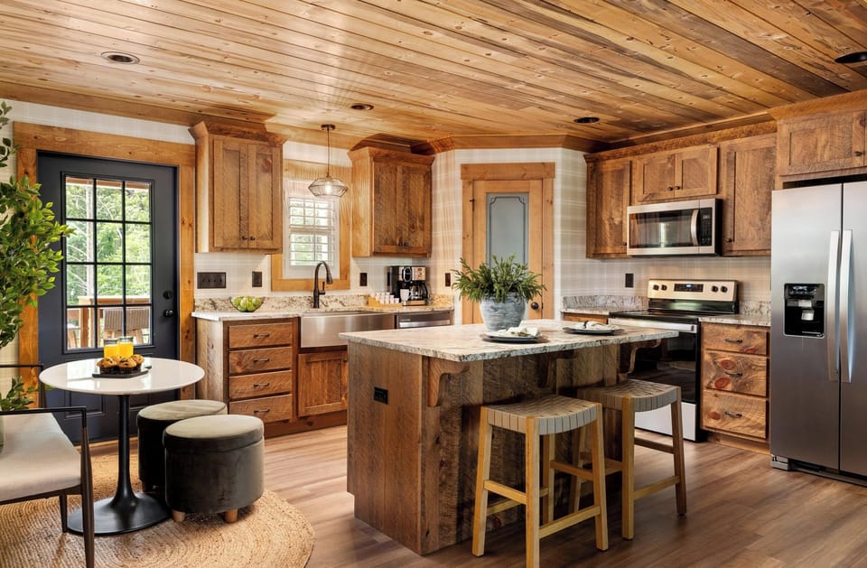 Gather around the oversized island, where high seating, wood cabinetry, and open space make every coffee, every meal, and every conversation feel effortless.