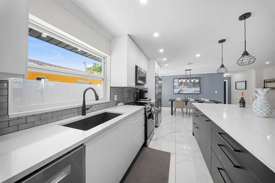 Fully equipped kitchen with black sink, stainless appliances, and bright window.