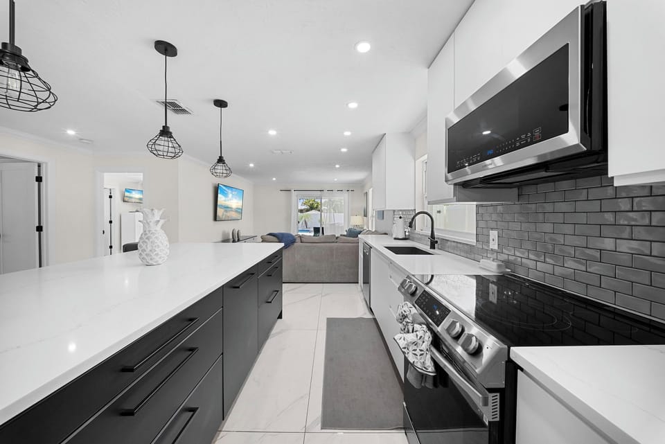 Quartz kitchen with stainless appliances and open flow to living area.