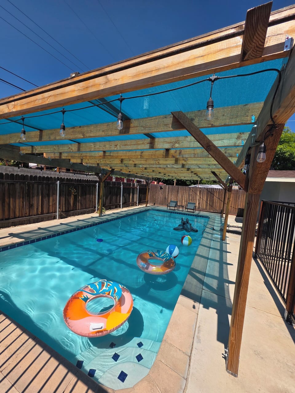 illuminated Gated pool, With beach balls, tubes, chairs, and table.