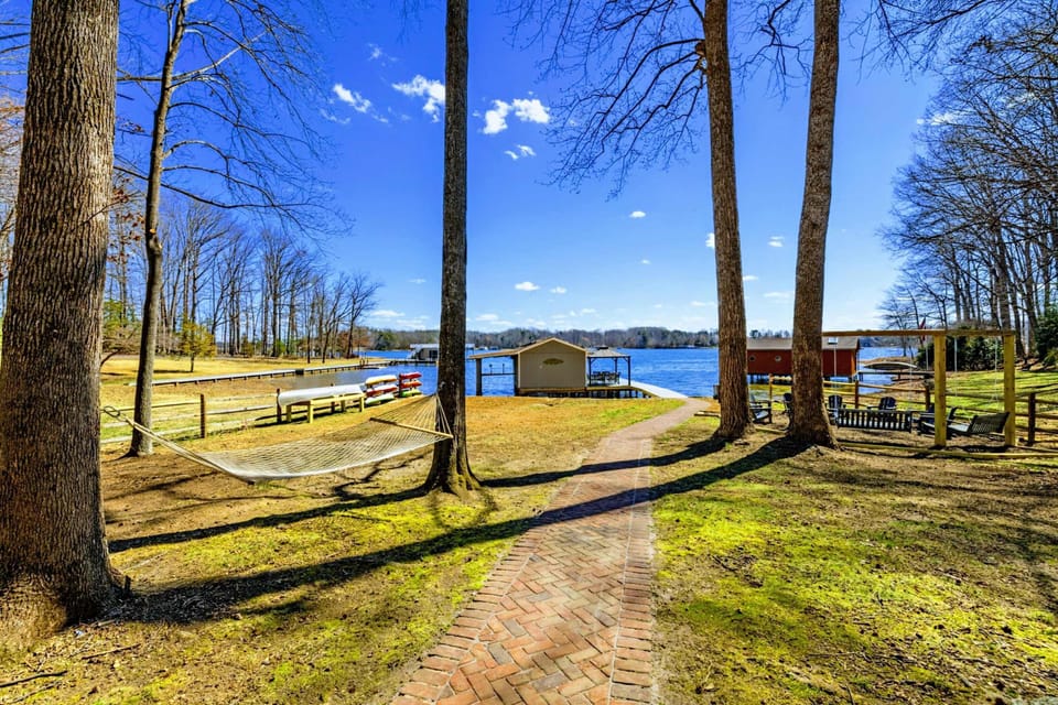 Hammock and Path - A hammock strung between tall trees sits along the brick path to the lake, with the boathouse visible ahead.