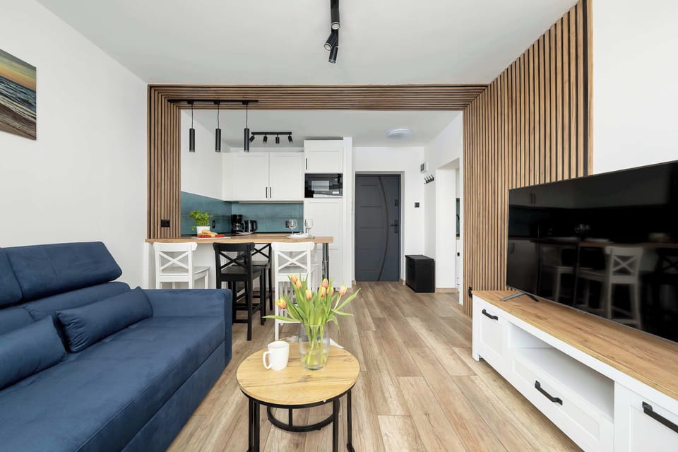 The living area emphasizes the plush blue sofa and elegant coffee table. Decorative elements like flowers and candles create a welcoming atmosphere. The space is ideal for relaxing after a long day.