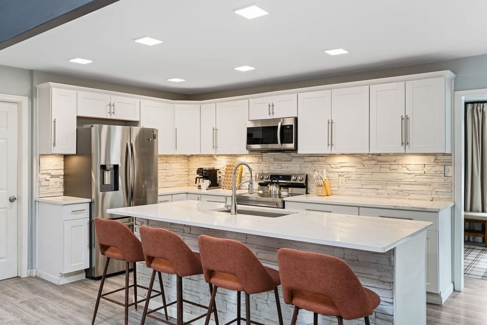 Modern kitchen with a large island, quartz countertops, and stainless steel appliances. Fully equipped for cooking, with seating for four at the island and a coffee station ready to start your day.