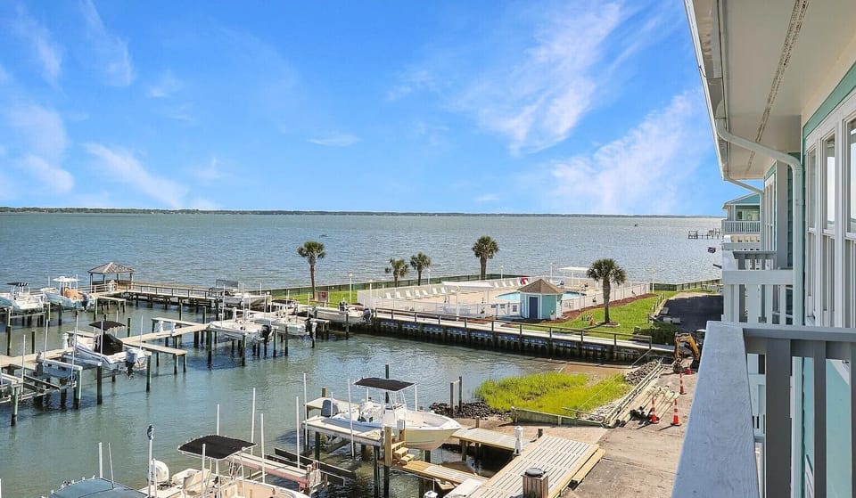 Waterfront view from property showing marina with boats and palm trees along the scenic coastline.