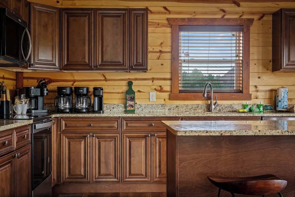 Warm wood-and-granite cabin kitchen with island and natural light