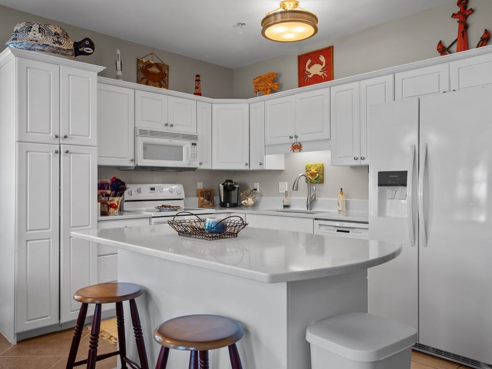 Your bright white kitchen offers modern appliances and breakfast bar seating, perfect for morning coffee or preparing vacation meals.