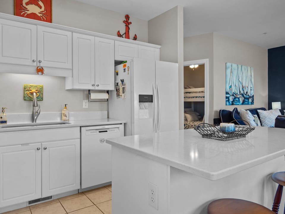 Your coastal-themed kitchen gleams with white cabinets and counters, perfect for preparing meals while enjoying ocean views.