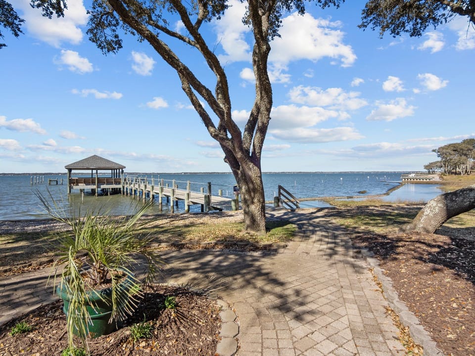 Waterfront property featuring private dock access and scenic lake views with mature shade trees and paved pathways.