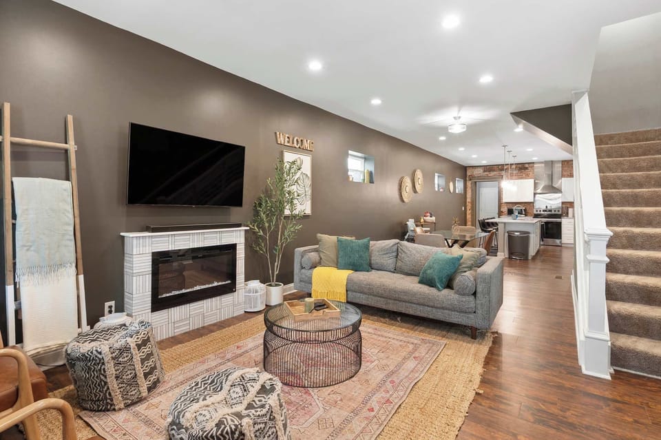 Spacious living area w/ a modern fireplace, large TV & open staircase.

