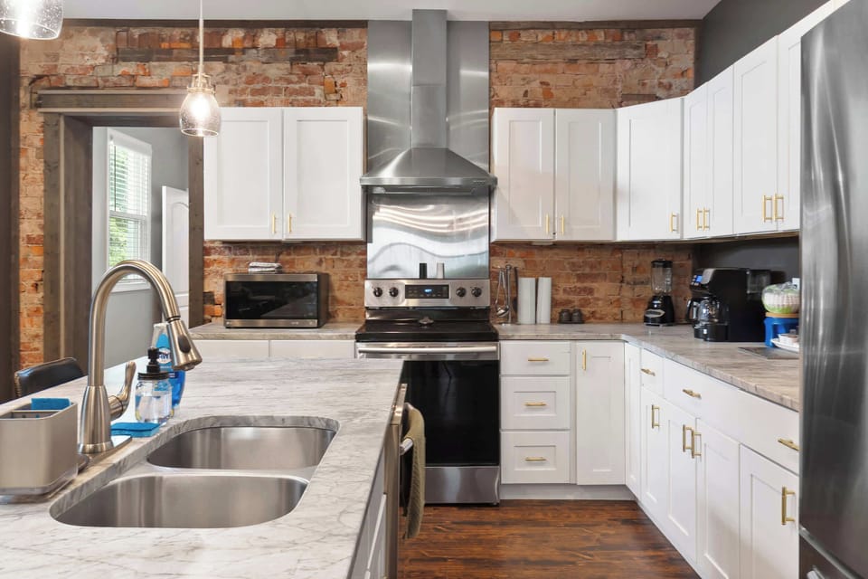 Bright kitchen w/ white cabinets, wood accents & a deep farmhouse sink.
