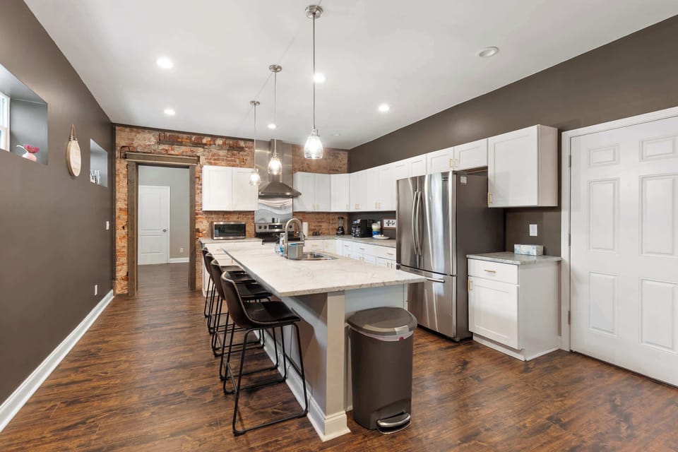Long open-concept kitchen & dining space w/ pendant lighting & seating for a crowd.
