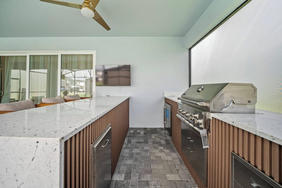 Experience our outdoor kitchen with stylish granite countertops and warm wood cabinetry. Cook on the built-in grill and stay cool with the ceiling fan while enjoying time with your guests in this perfect entertaining space.