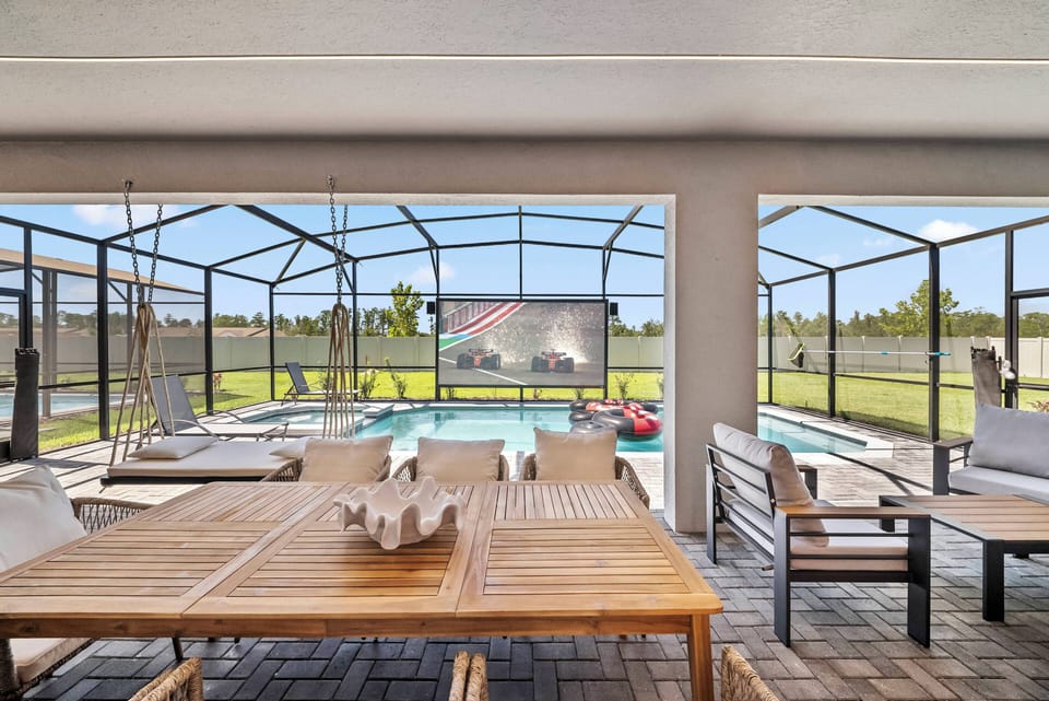 Discover a sunlit oasis with a spacious screened patio that leads to a sparkling pool, perfect for lounging. Enjoy the natural wood dining table and sleek outdoor seating, providing an ideal space for relaxation and gatherings.