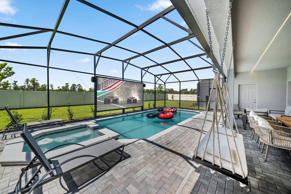 Step into a sun-drenched oasis featuring a sleek pool surrounded by modern lounge chairs. The inviting outdoor space includes a cozy dining area and a large screen for movie nights under the stars, perfect for relaxation and fun.
