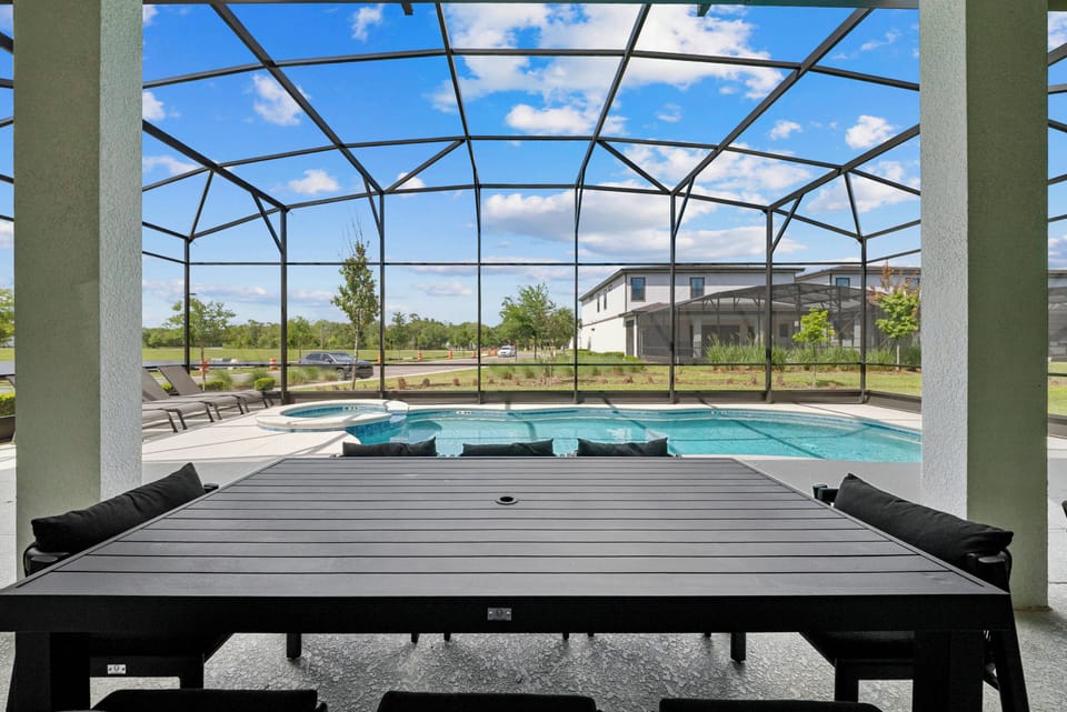Step outside to a spacious patio with a large dining table, ideal for meals overlooking the crystal-clear pool. The screened enclosure keeps you comfortable as you soak up the sun and enjoy the lush greenery around you.