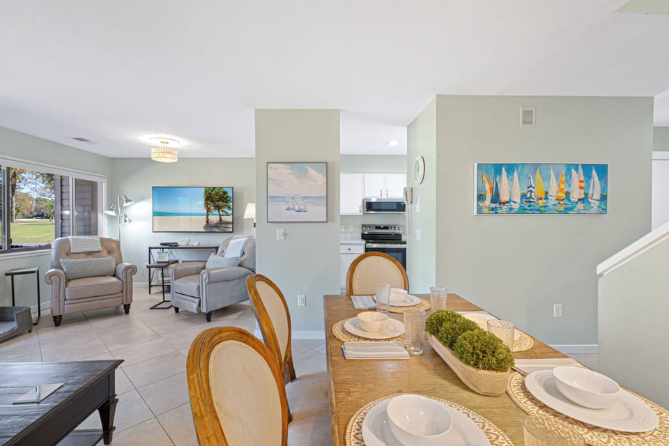 The dining area flows seamlessly into the living room and kitchen, creating a layout that feels open, connected, and easy to enjoy. Natural light carries throughout the space, while soft coastal colors keep everything feeling calm and comfortable.