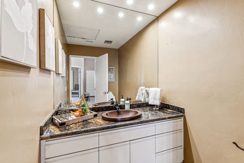 Bathroom vanity w/ granite counter, mirror & neatly arranged essentials