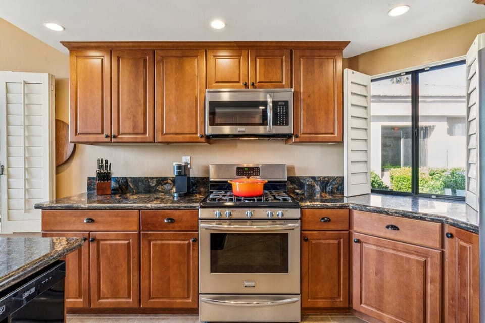 Well-equipped kitchen w/ warm wood cabinetry, ample counter space & window views