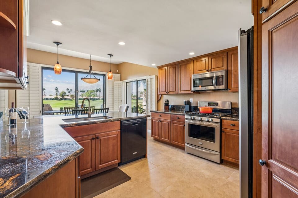 Spacious kitchen w/ warm wood cabinetry, stainless appliances & island for easy meal prep