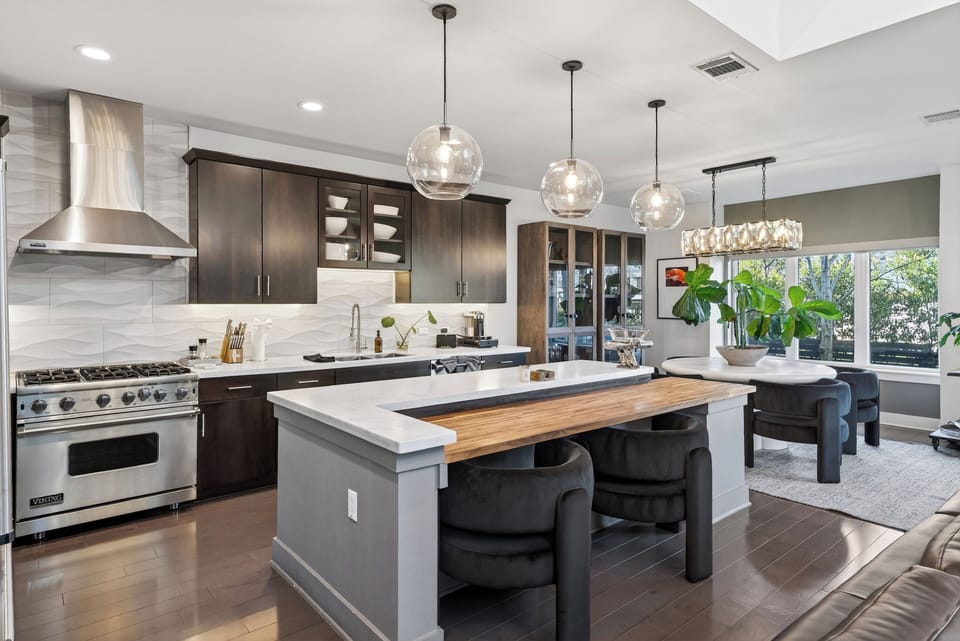 Chef’s kitchen with premium appliances, waterfall island seating, and an open layout that flows into the dining area.