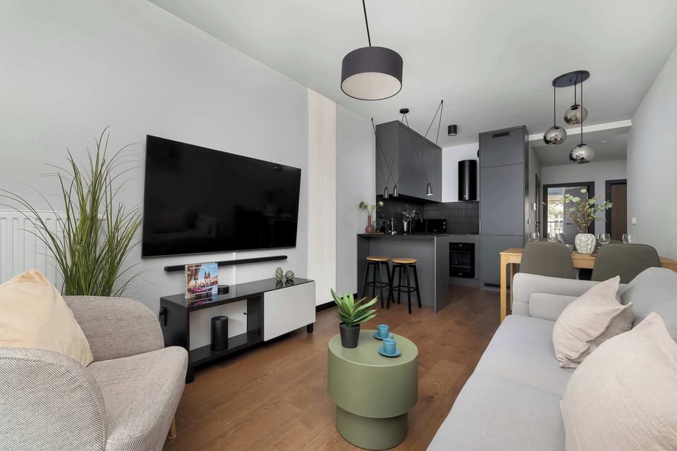 A living room angle showing a TV wall and seating area with subtle decor. The interior design is clean and modern.