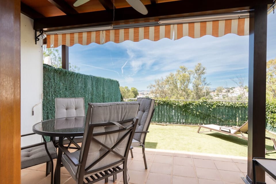 Dine open-air on the private, fully fenced patio, offering a secluded space for your morning coffee or evening meals. The outdoor seating area is shaded, providing a comfortable retreat from the afternoon sun.