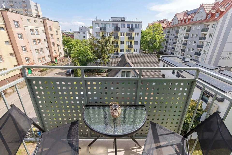 A balcony with a small table and chairs overlooking nearby residential buildings.