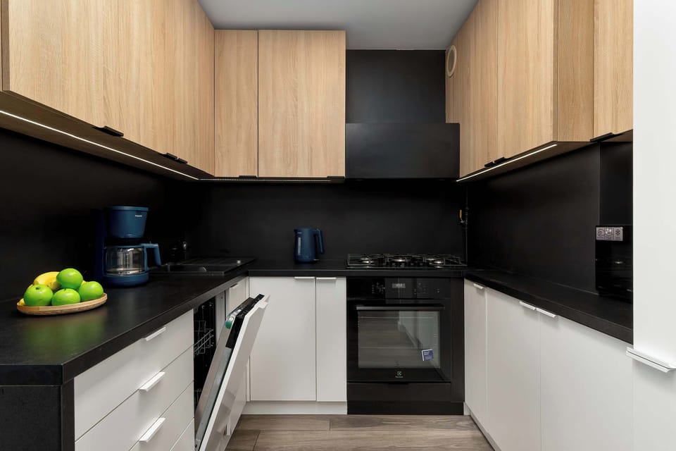 Another angle of the sleek kitchen highlighting the contrast between black surfaces and wood finishes.