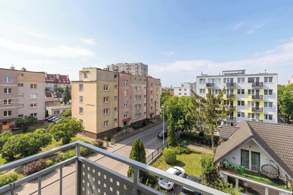 A wider balcony view capturing surrounding apartment blocks and a sunny sky.